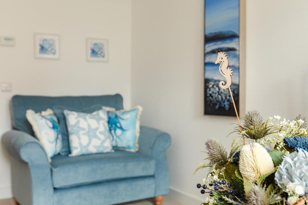 a living room with a blue couch and a vase of flowers at Wee Jules By The Sea in Anstruther