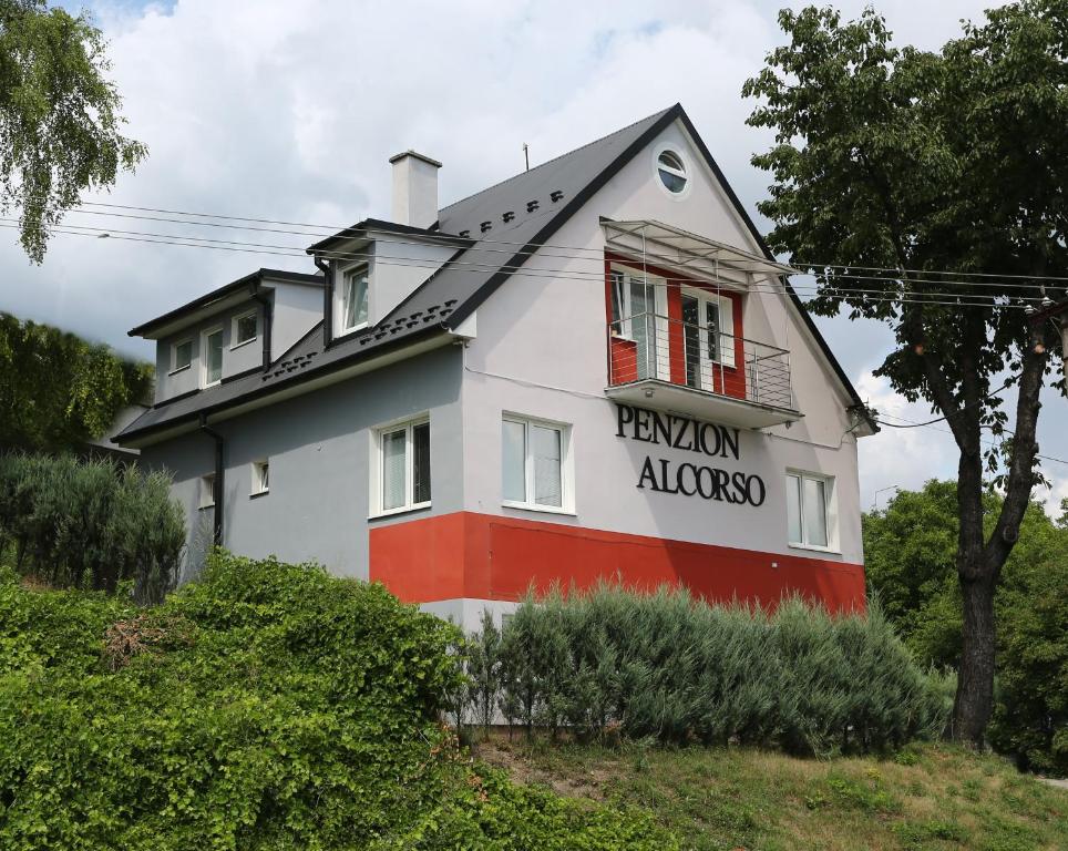 una casa blanca y roja con un cartel. en Alcorso Pension en Banská Bystrica