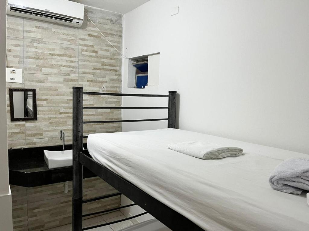a bedroom with a bed and a bathroom with a sink at Tia Preta Pousada in Morro de São Paulo
