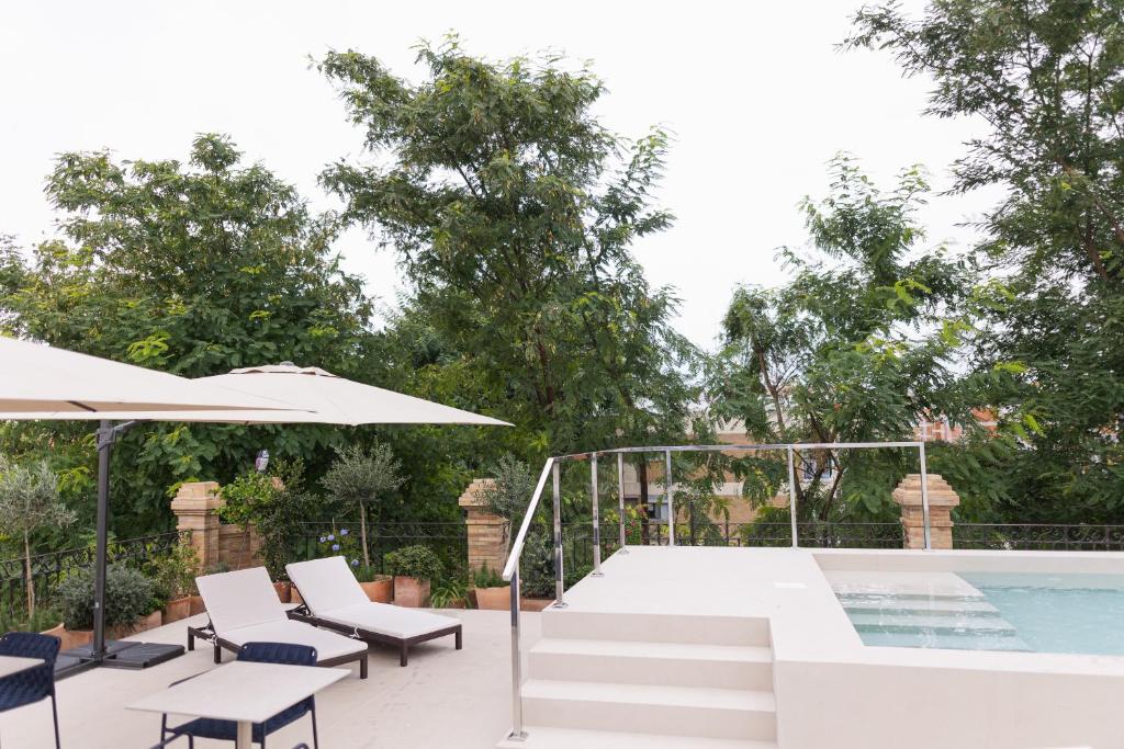 a patio with a pool and chairs and an umbrella at Cavalta Boutique Hotel GL in Seville
