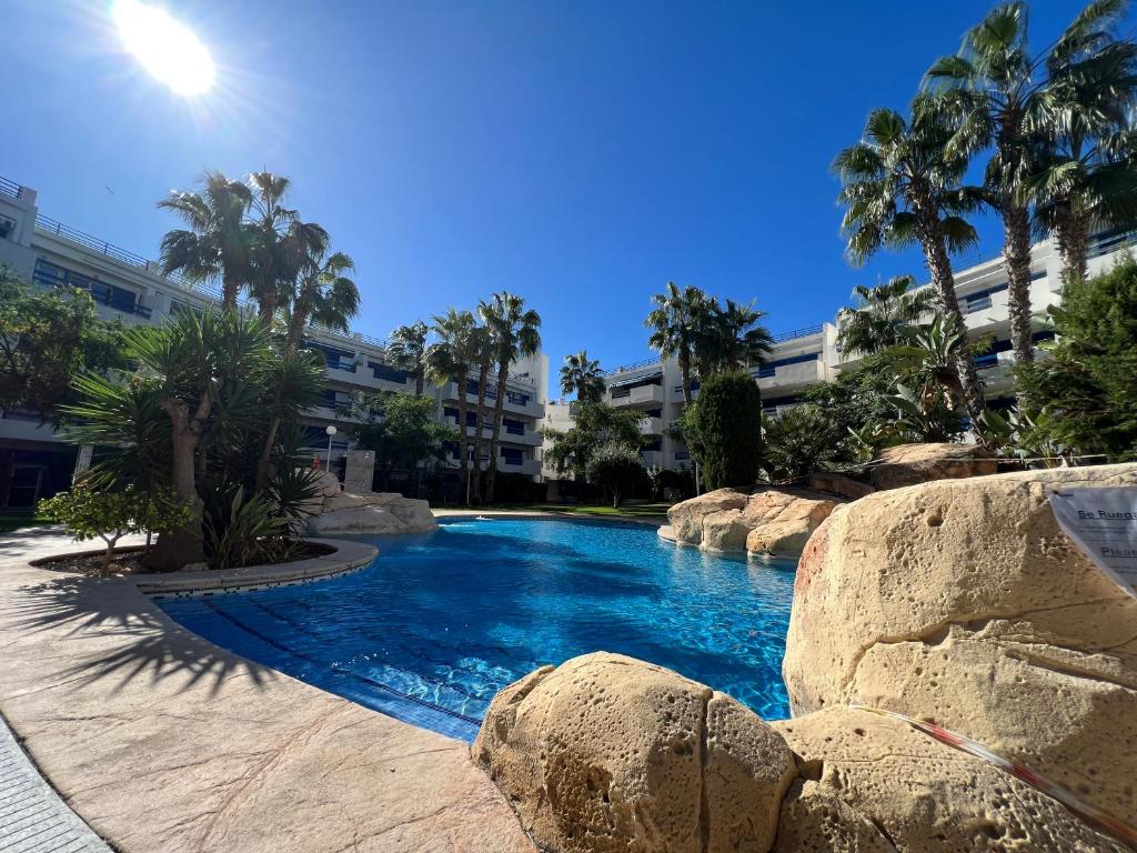 una piscina con rocce di fronte a un edificio di La Calma - one bedroom apartment by the pool in Playa Flamenca a Playas de Orihuela