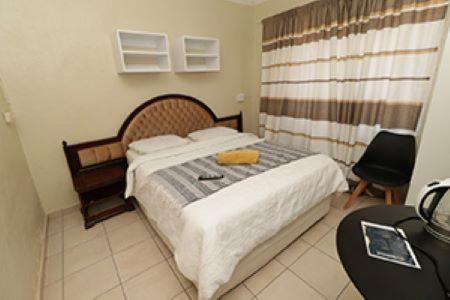 a bedroom with a bed and a table and a chair at Quintax Guest House in Pretoria