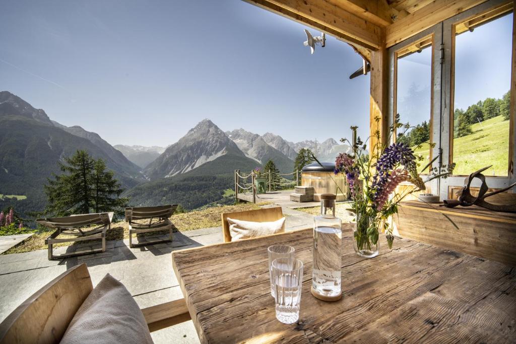 a wooden porch with a table with a view of mountains at Bergchalet Flöna in Scuol