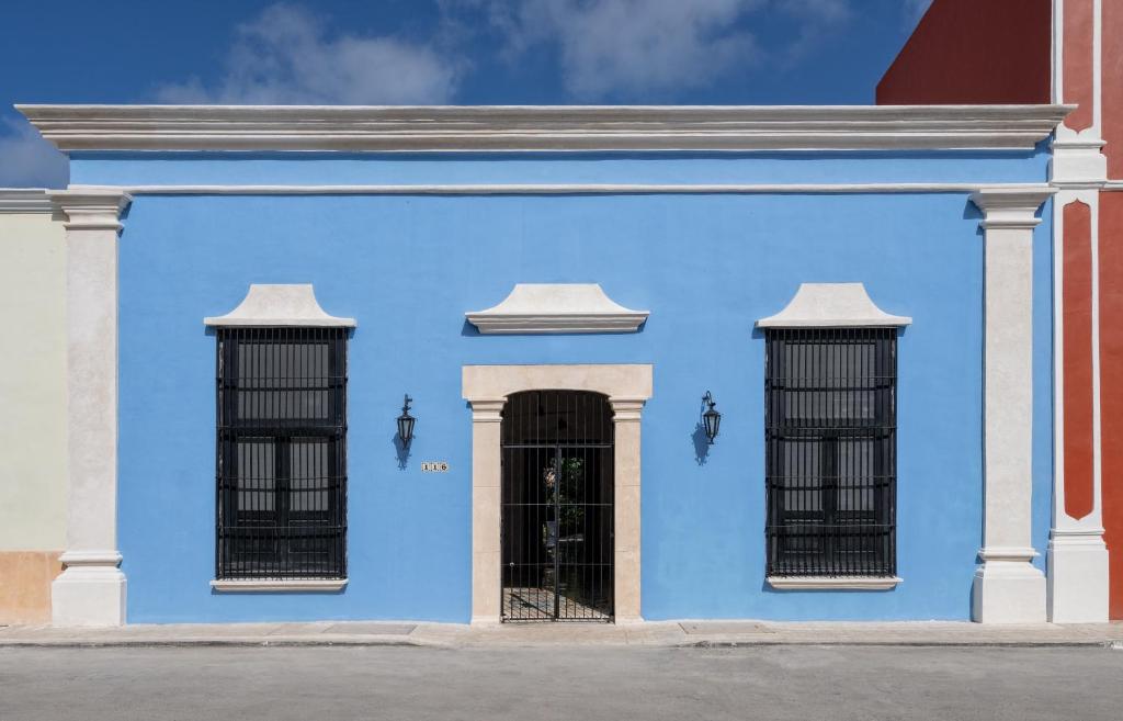 un edificio azul con dos ventanas de barrica negra en Casa Clorinda, en Campeche