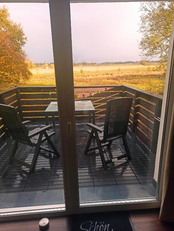 a screened porch with two chairs and a table at Schöne Ferienwohnung mit Balkon auch für Handwerker und Monteure in Borsfleth