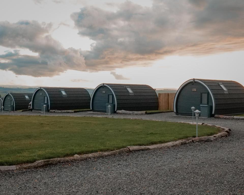 a row of green domed buildings on a field at Timber Valley Pods in Galston