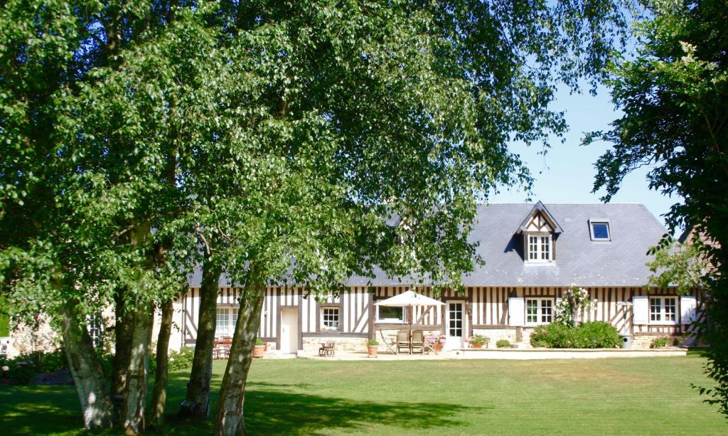 una casa grande con árboles delante de ella en La Longère, en Bonneville-sur-Touques