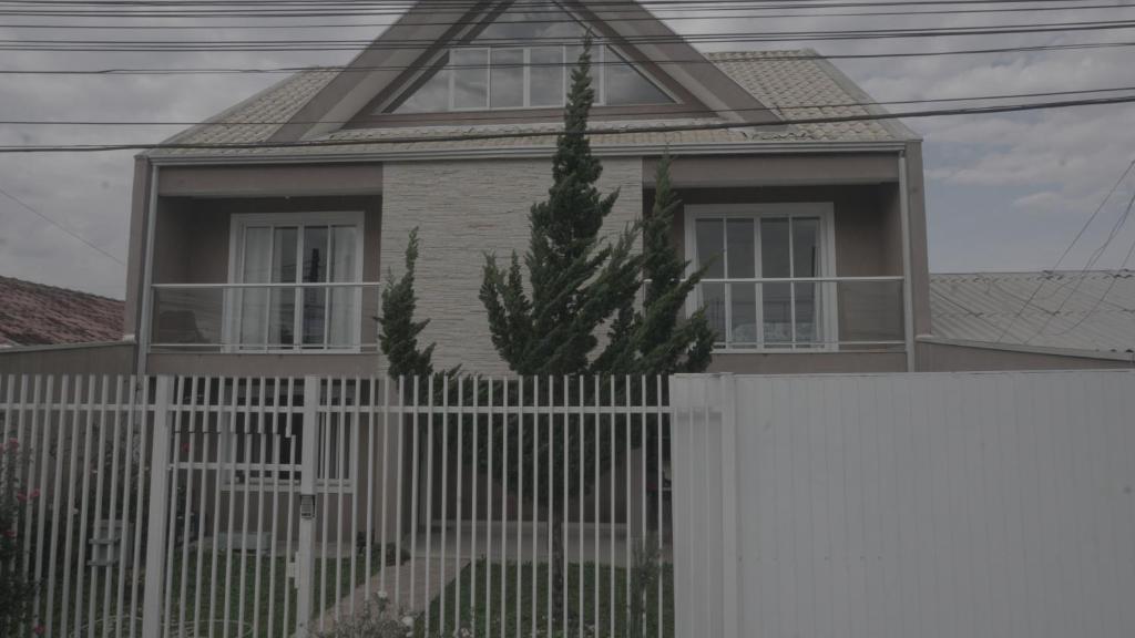 dom z białym płotem i kaktusem w obiekcie Hub House w mieście Kurytyba