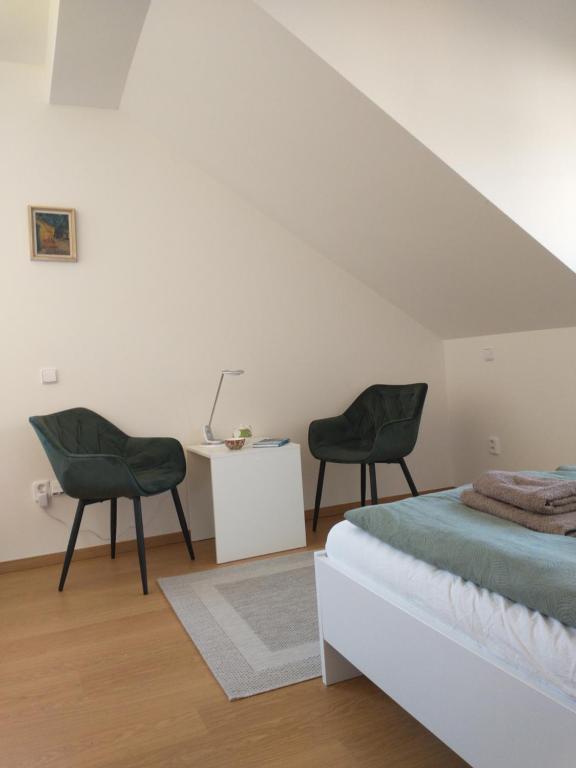 a bedroom with two green chairs and a bed at Apartment Felicitas in Kašperské Hory
