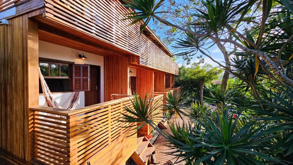 a wooden house with a balcony with palm trees at Vila no Rosa Hospedaria in Praia do Rosa