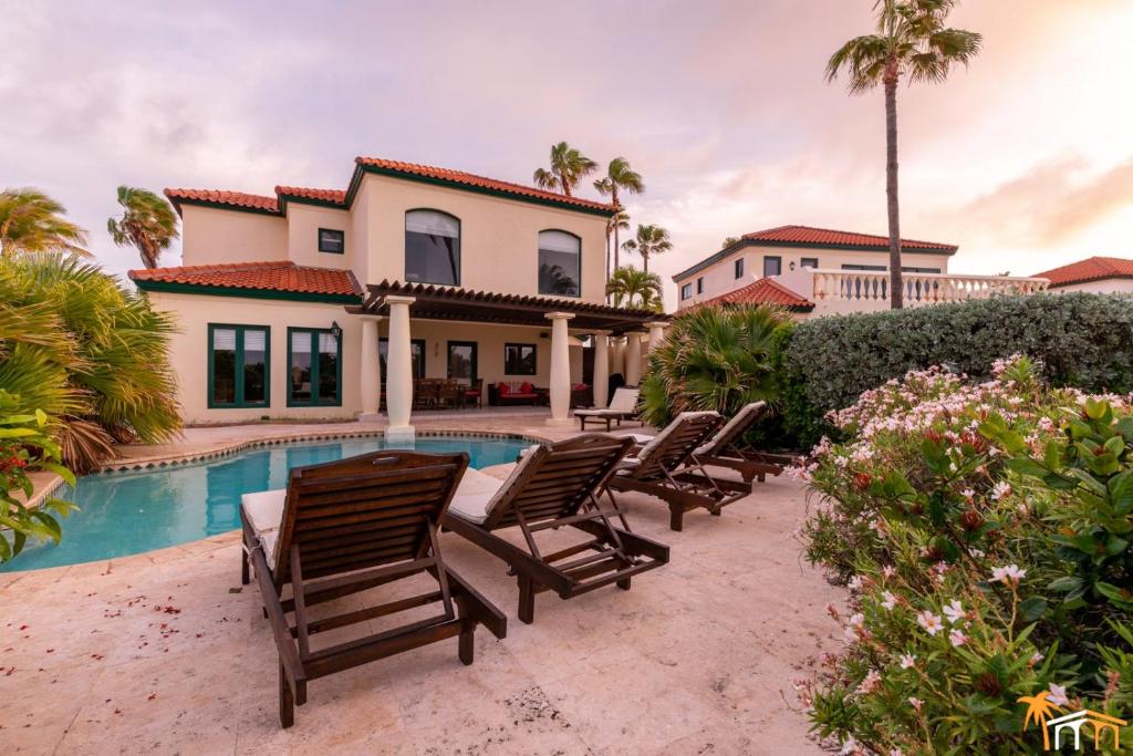 a villa with a swimming pool and lounge chairs at Luxurious Ocean View Tierra del Sol Villa in Palm-Eagle Beach