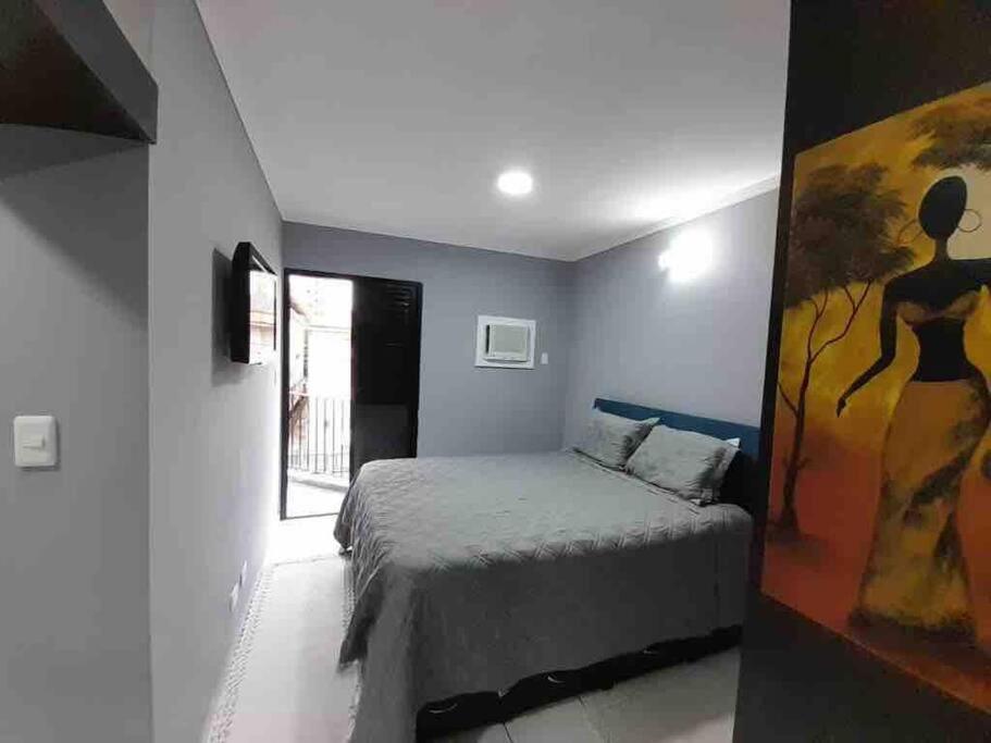 1 dormitorio con 1 cama y una pintura en la pared en Flat Palladium, en São Vicente