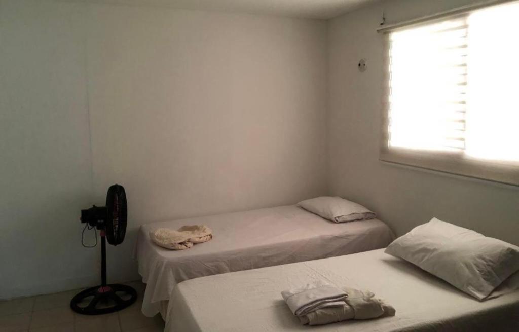 2 Betten in einem kleinen Zimmer mit Fenster in der Unterkunft Casa prado alto in Barranquilla