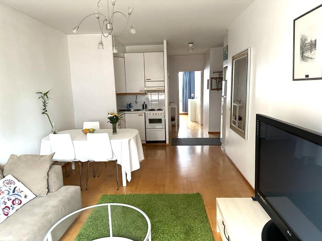 ein Wohnzimmer mit einem Sofa und einem Tisch sowie eine Küche in der Unterkunft Spacious 2 rooms apartment in Helsinki Design District, own balcony in Helsinki