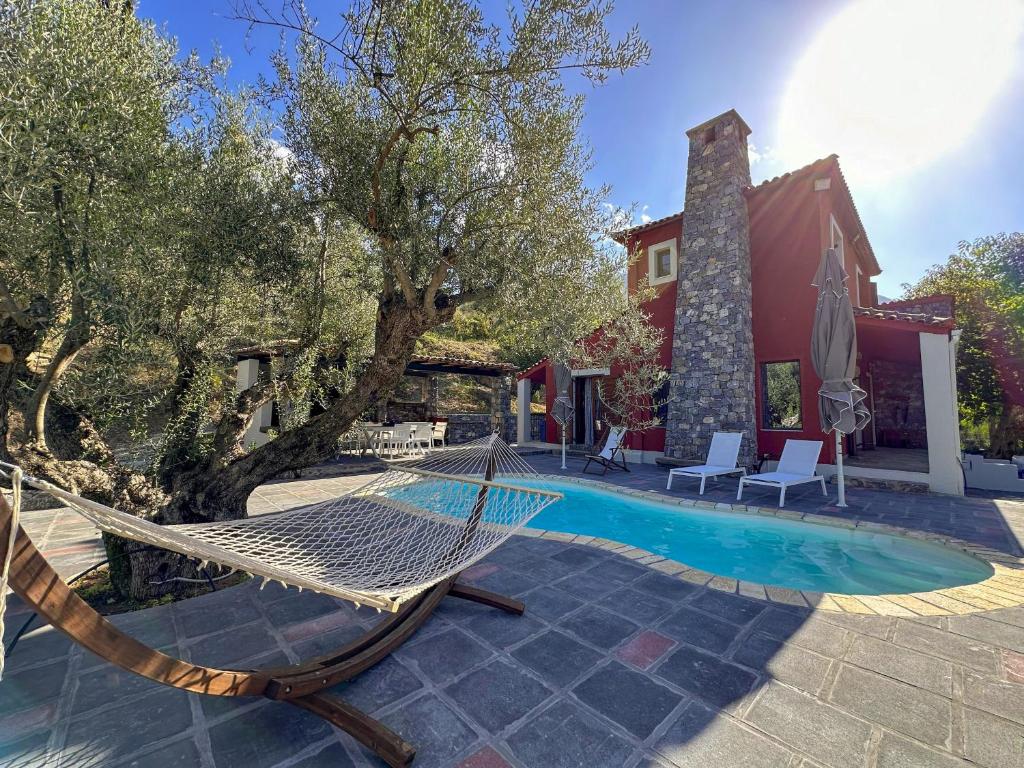 a hammock in front of a house with a pool at Casa Calma Villa Greece in Diakopto