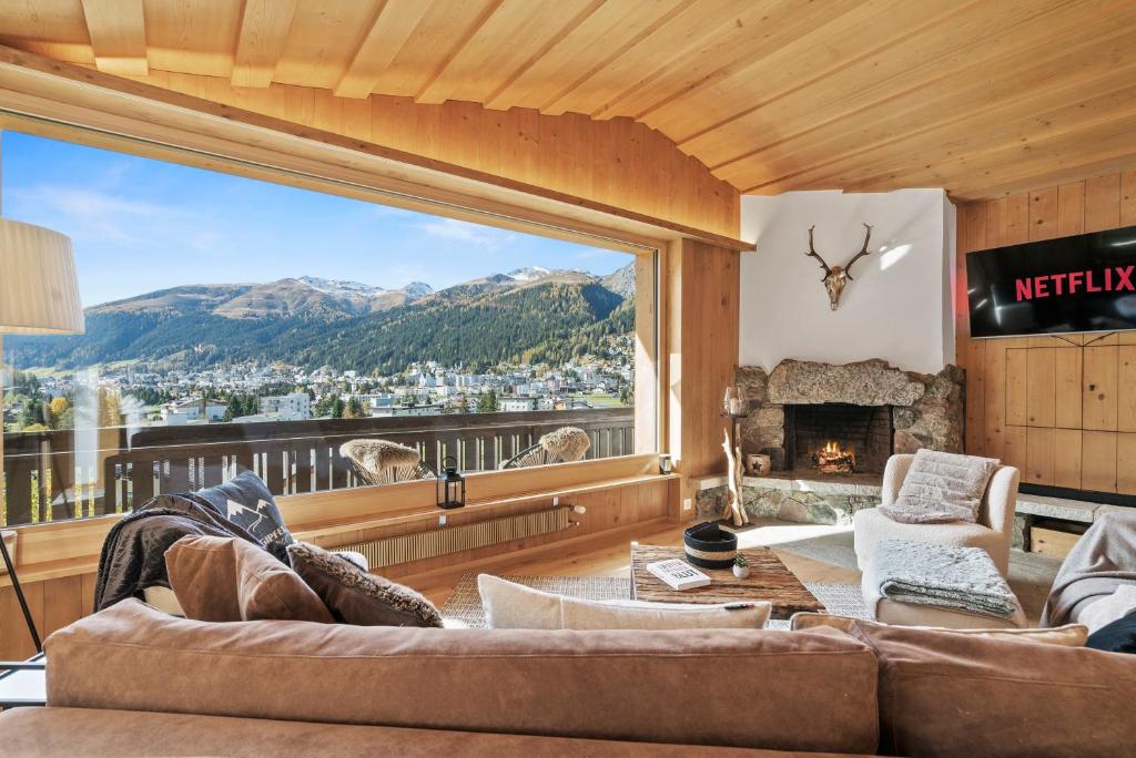 a living room with a large window with a mountain view at A&Y Chalet zum goldenen Hirsch in Davos