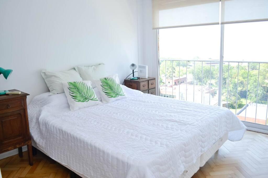 1 dormitorio con cama blanca y ventana grande en Libertador 2785 by depptö in 