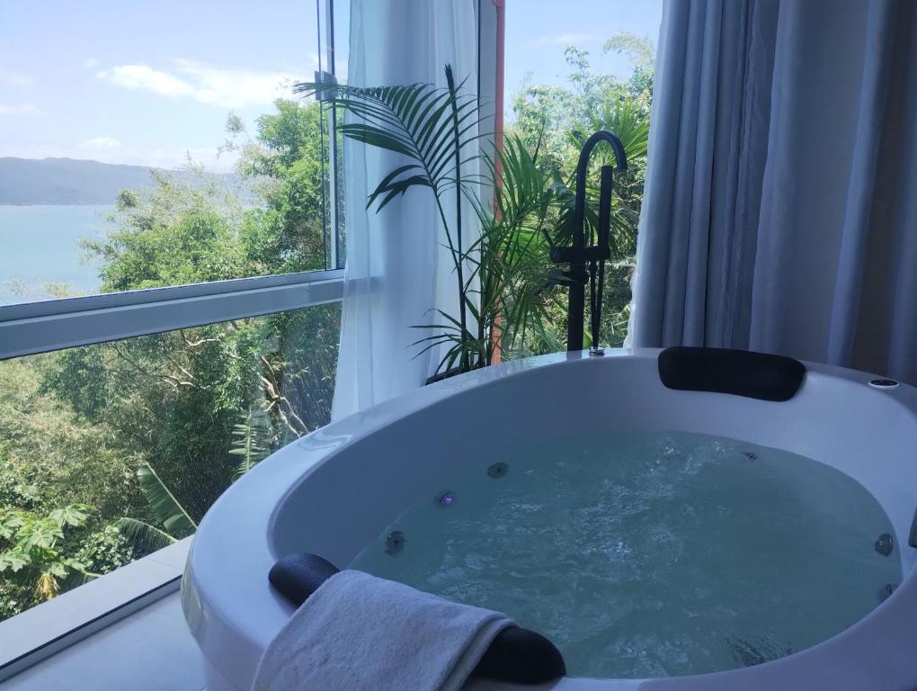 bañera en una habitación con ventana en North Suíte, en Florianópolis