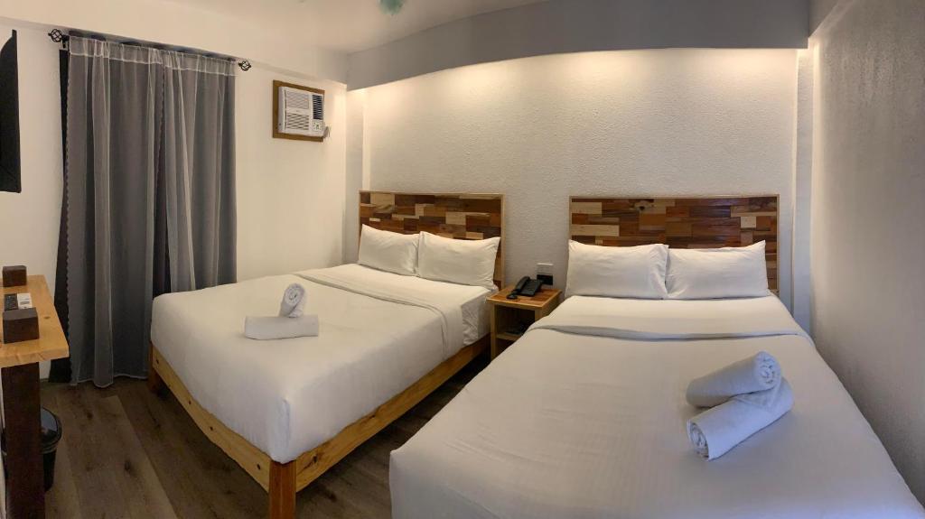 two beds in a hotel room with white sheets at El Puerto Boracay Shore in Boracay