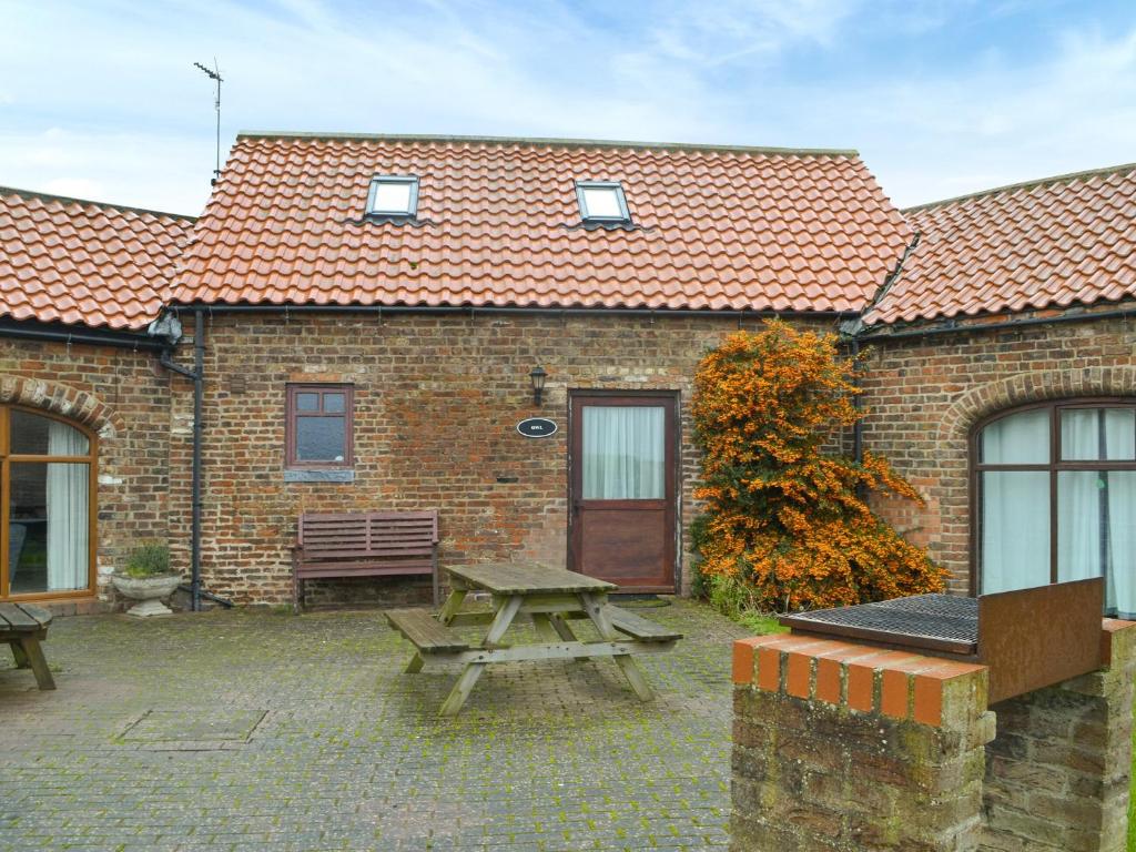 a brick building with a picnic table and a bench at Owl Cottage in Flamborough