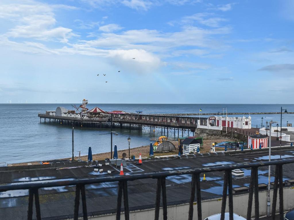 a pier next to the ocean with vehicles on it at Coastal Charm in Herne Bay