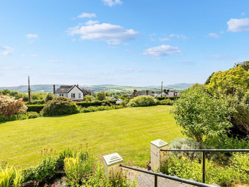 una vista desde el jardín de una casa con un gran césped en The Grooms Cottage-uk45659 en Bishops Castle