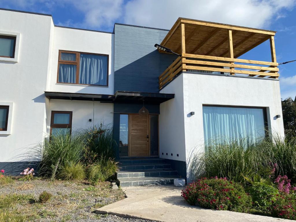 une maison blanche avec une porte en bois dans l'établissement Chalet playa hermosa, à Pichilemu