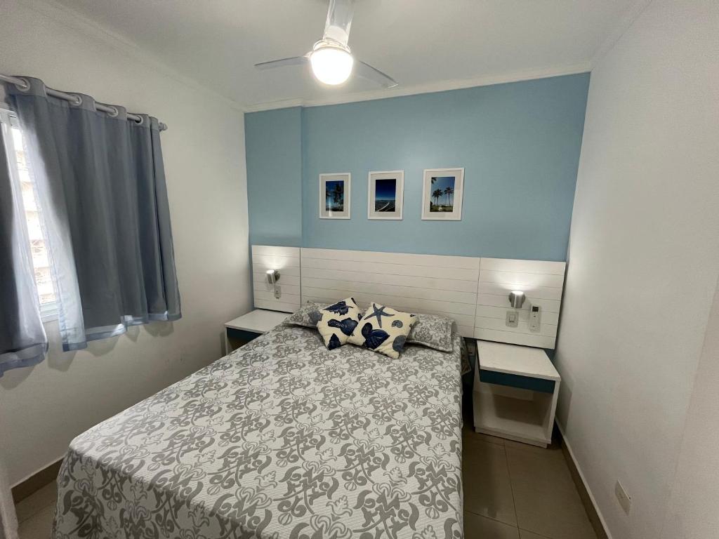 1 dormitorio con cama y pared azul en FLAT RIVIERA COM AR A 150 m DA PRAIA !, en Riviera de São Lourenço