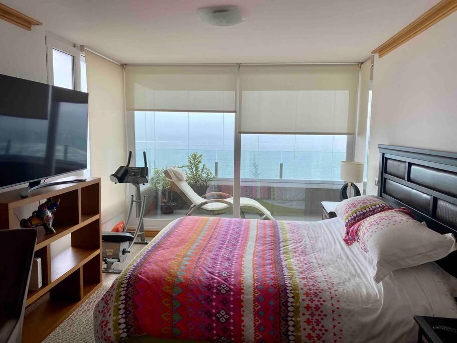 a bedroom with a large bed and a large window at Hermoso y tranquilo departamento frente al mar. in Concón