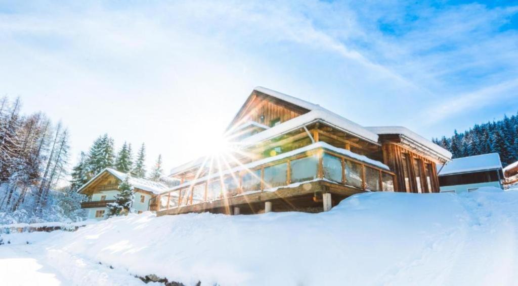 ein Haus im Schnee mit der Sonne dahinter in der Unterkunft Panorama-Chalet Alpenglöckchen in Stadl an der Mur