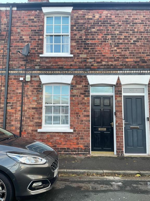 a brick house with a black door and a car parked in front at George Street Beverley in Beverley