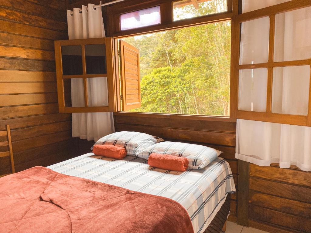 um quarto com uma cama com uma janela em Chalés Requinte em Pedra Azul em Pedra Azul