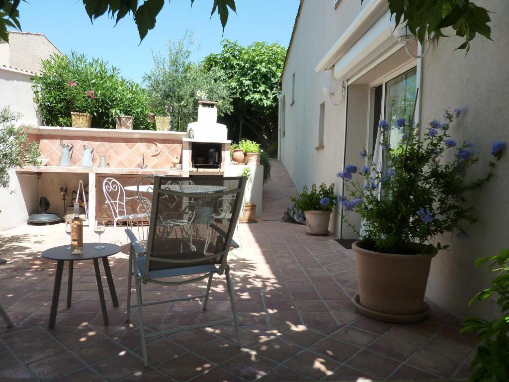 a patio with a table and a chair and some plants at A l'ombre du figuier in Lorgues