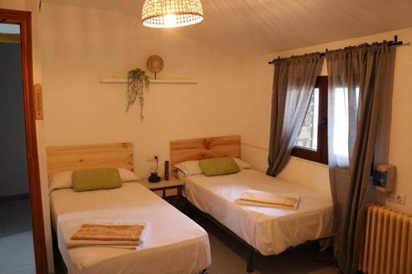 1 dormitorio con 2 camas y ventana en El Refugio Valdelinares Gastro Hostal, en Valdelinares