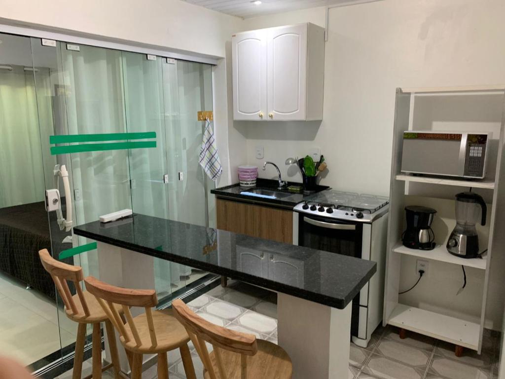 a kitchen with a counter and three chairs in it at Casa em Arraial do Cabo na praia grande in Arraial do Cabo