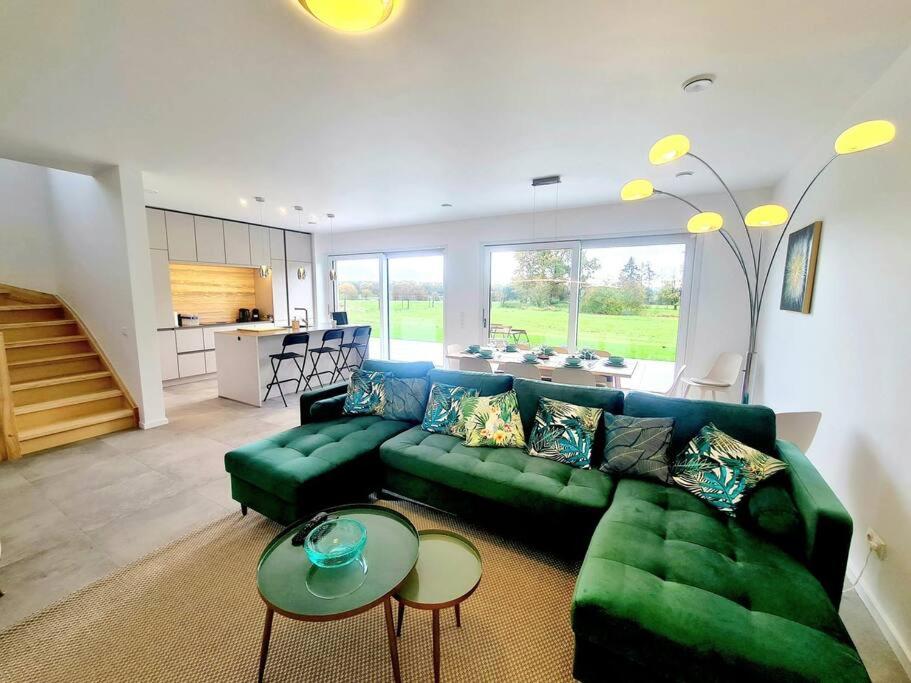 uma sala de estar com um sofá verde e uma cozinha em Spacious&Luxurious 5 bedrooms House 