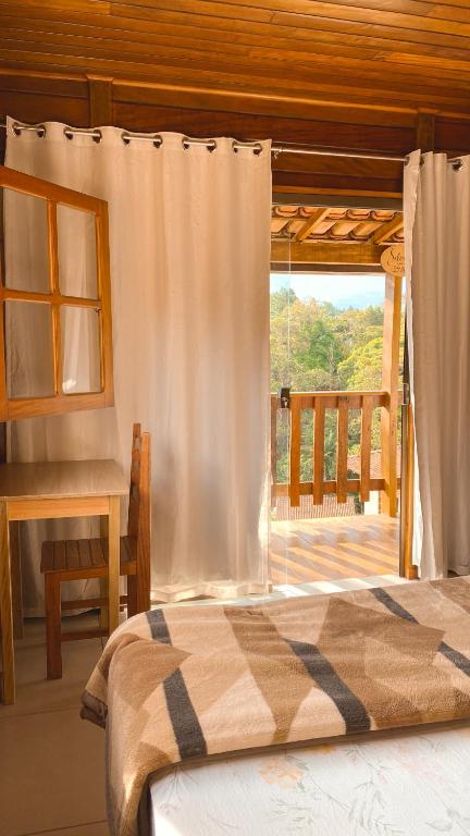 a bedroom with a bed and a window with a porch at Chalés Requinte em Pedra Azul in Pedra Azul