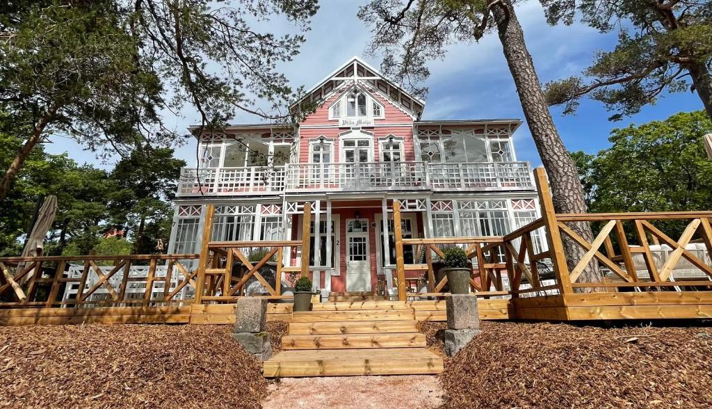 Cette grande maison rose est entourée d'une terrasse couverte. dans l'établissement Villa Maija 1 Eastside, à Hanko