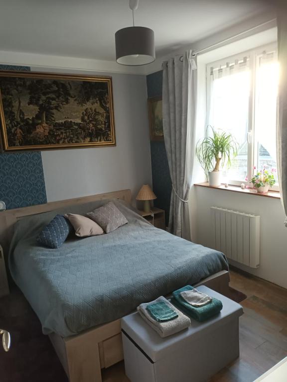 1 dormitorio con 1 cama con edredón azul y ventana en Chambre bleue bien équipée chez Fred, en Gorron
