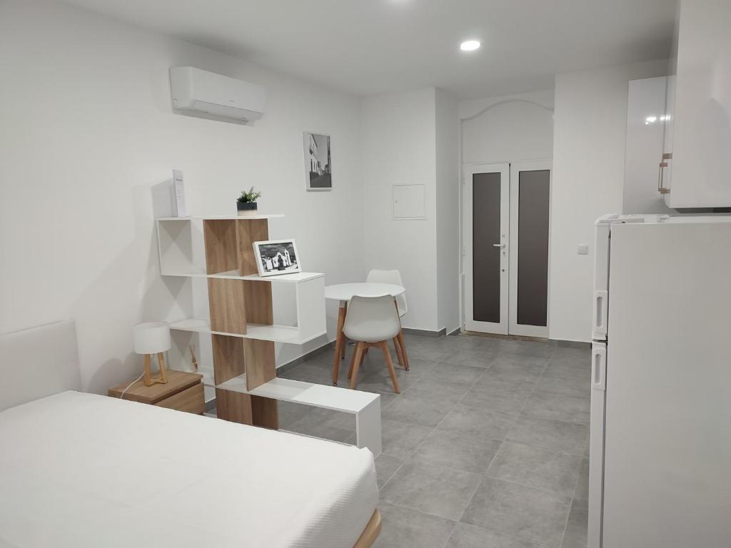 a white room with a table and a refrigerator at Penedo Grande suítes Estúdio in São Bartolomeu de Messines