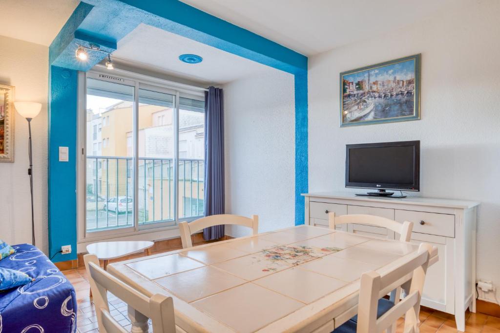 une salle à manger avec une table et une télévision dans l'établissement La Maison des Sarrazins, au Cap d'Agde