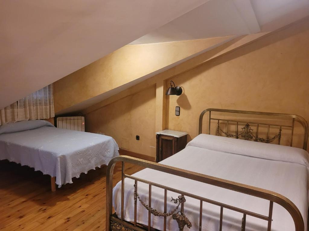 Cadalso de los VidriosにあるCasa Rural La Vidのベッドルーム(ベッド2台付)が備わる屋根裏部屋です。