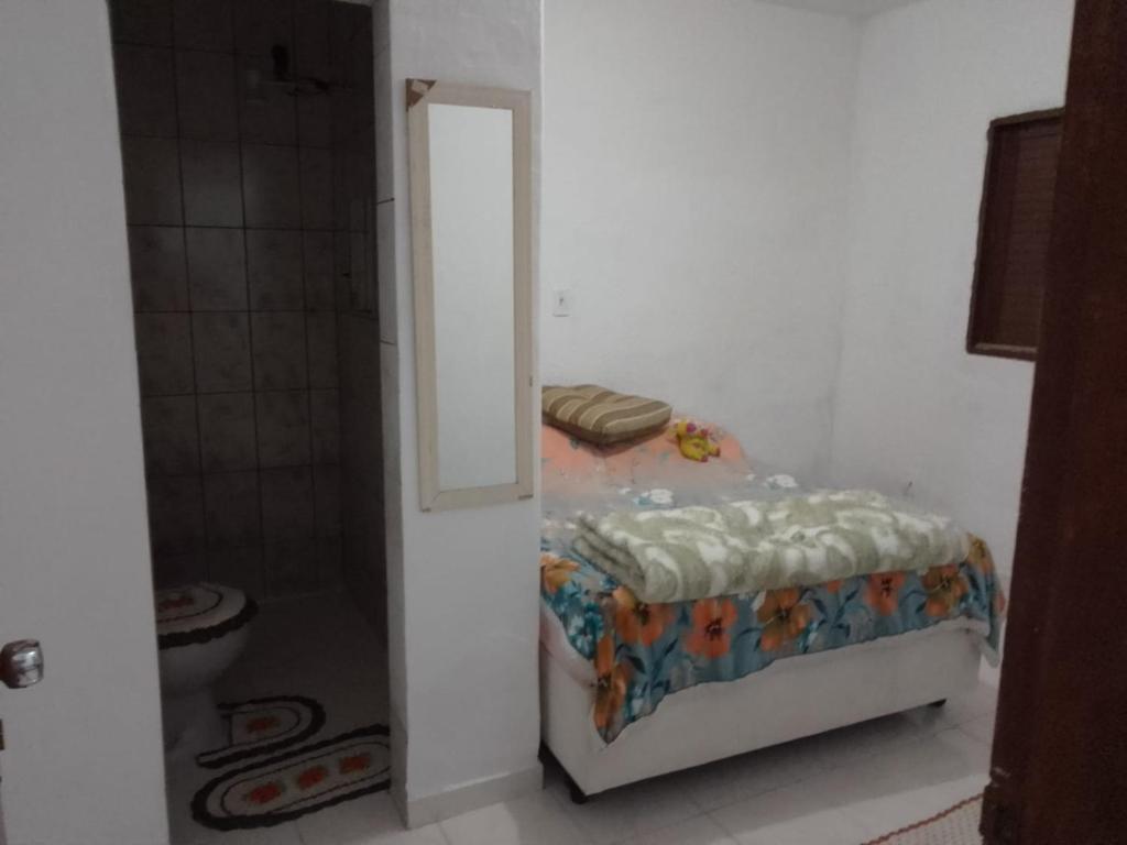 um pequeno quarto com uma cama e um chuveiro em Casa para temporada no Guarujá