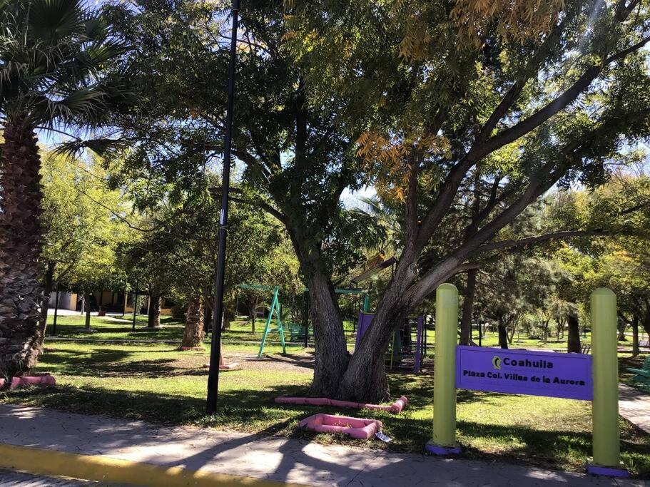 un parc avec un arbre et un panneau dans l'herbe dans l'établissement Departamentos nuevos, con excelente ubicación, à Saltillo
