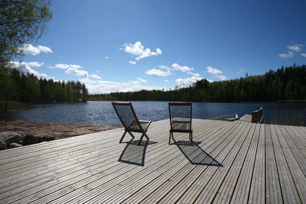 2 chaises assises sur un quai à côté d'un lac dans l'établissement Villa Rajala, à Imatra