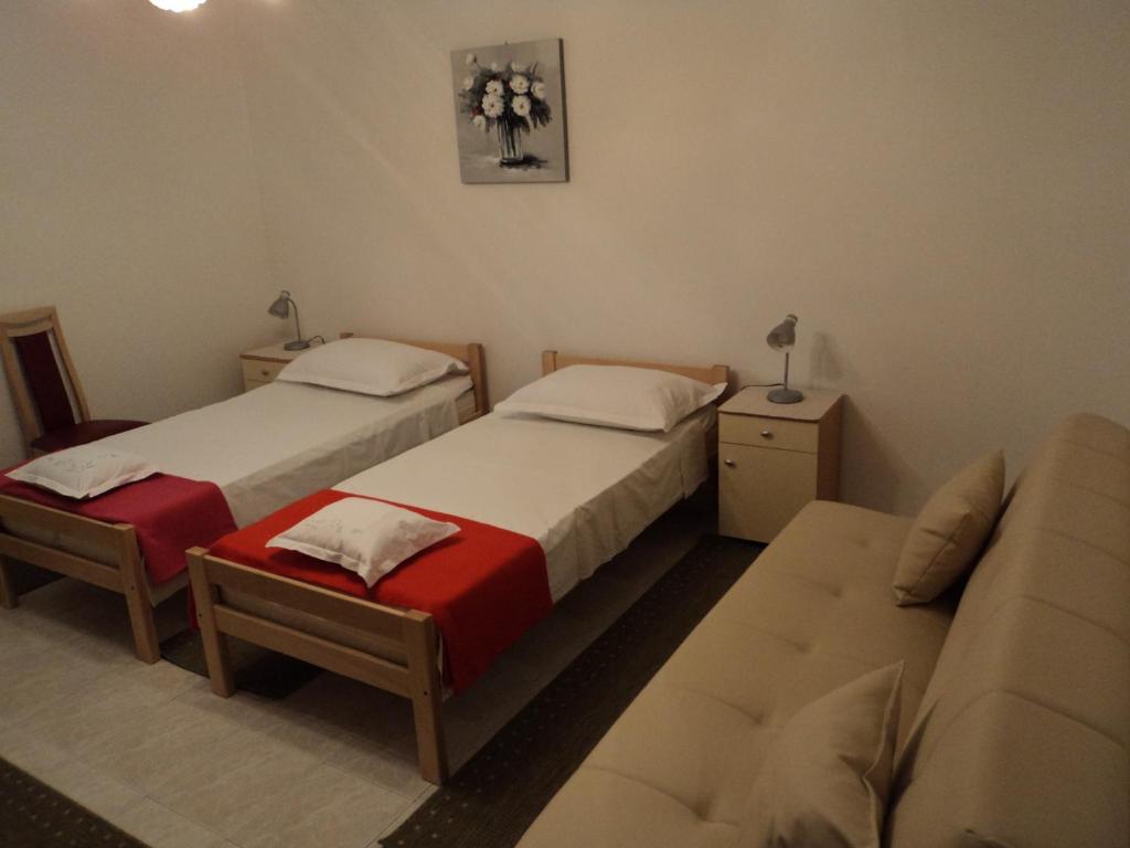 two beds in a room with a couch and a couch at Apartments Lička 25 in Split