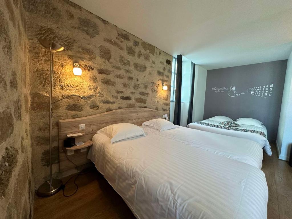 Best Western Le Pont d'Or في فيجيا: غرفة نوم بسريرين وجدار من الطوب