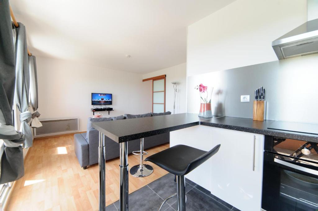 a kitchen and living room with a black counter top at Le Marnois-Gare in Noisy-le-Grand