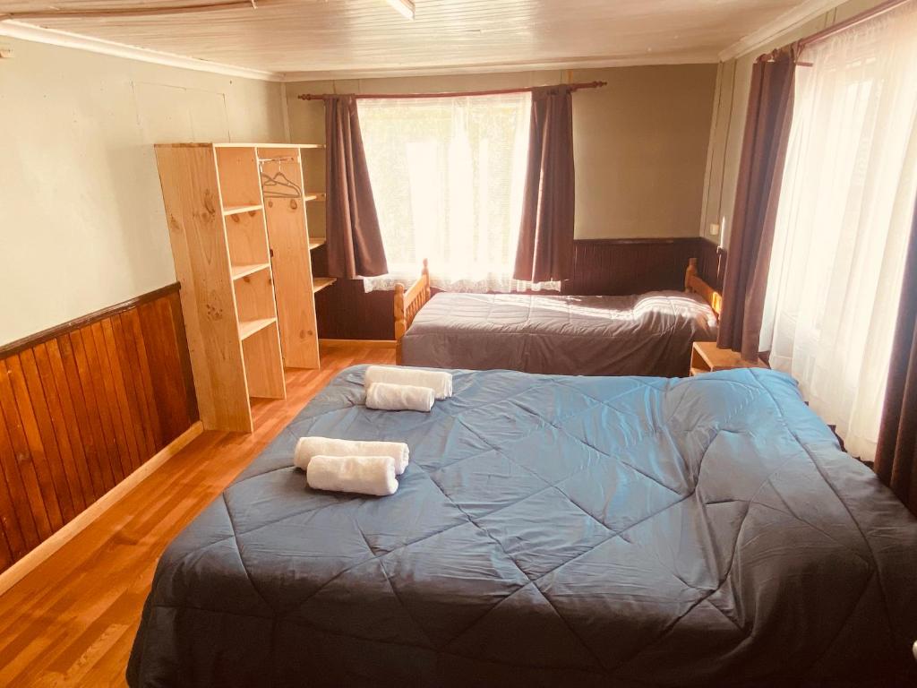 ein Schlafzimmer mit 2 Betten und Handtüchern darauf in der Unterkunft HOSTAL MIRAFLORES in Puerto Natales