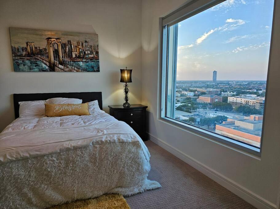 a bedroom with a bed and a large window at Luxury Highrise in Midtown - Skyline Views and Chic Decor in Houston